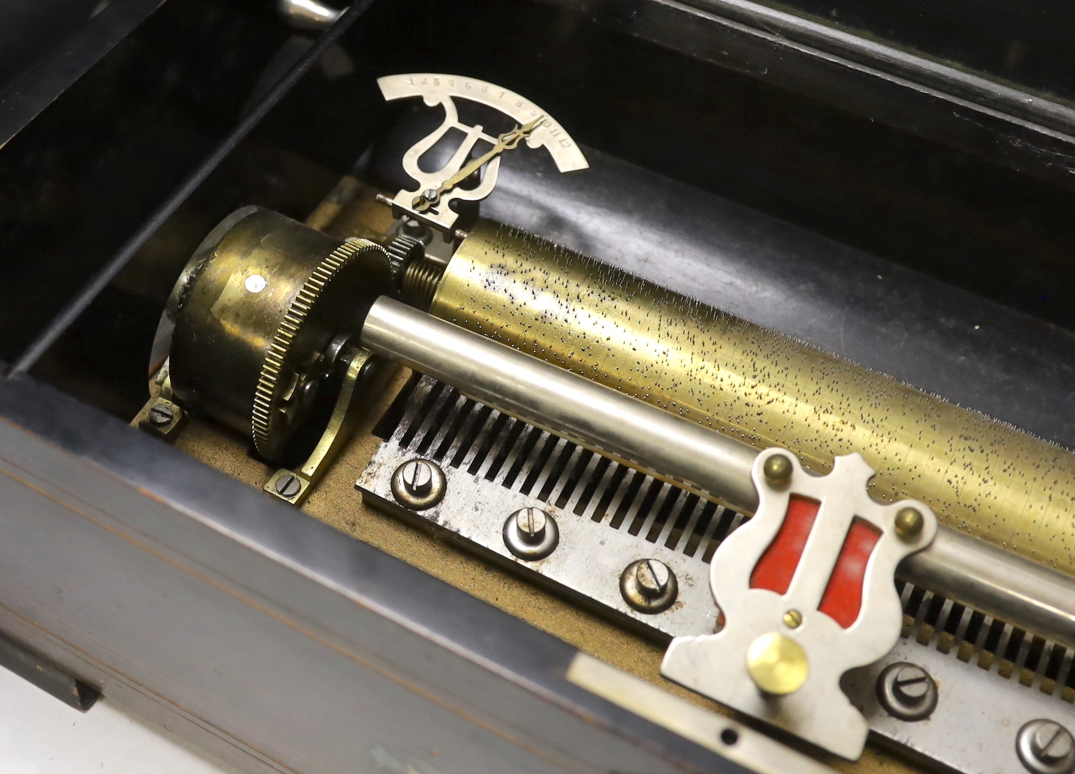 A late 19th century Swiss inlaid rosewood cased musical box, single cylinder with a 52 note comb playing twelve airs, tune indicator below glass dust cover, with tune list on underside of lid, 51 x 16 x 25cm